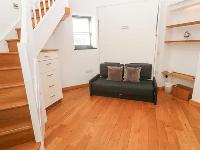 a living room with a black couch and stairs at The Observatory Tower in Falmouth