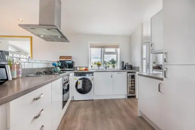 a kitchen with white cabinets and a washer and dryer at 2 Bed in St. Merryn oc-a30663 in St Merryn