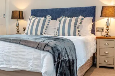 a bedroom with a bed with a blue headboard and two lamps at 2 Bed in St. Merryn oc-a30663 in St Merryn