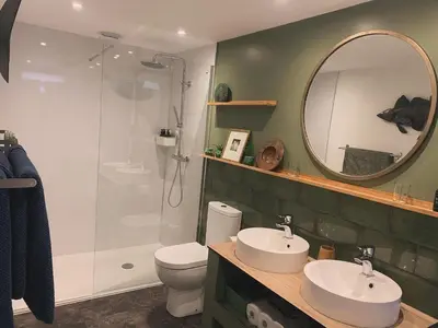 a bathroom with a shower and two sinks and a mirror at Field End in Liskeard