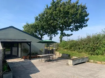 a patio with a table and a green umbrella at Field End in Liskeard