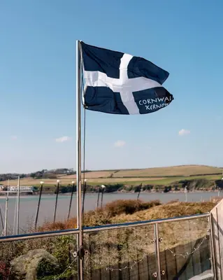 a flag flying over a fence next to a river at Bijou Beachfront Gem, Rock in Padstow
