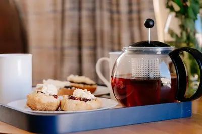 a plate of pastries and a tea pot on a table at Bijou Beachfront Gem, Rock in Padstow