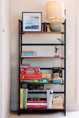 a book shelf filled with books and a lamp at Bijou Beachfront Gem, Rock in Padstow