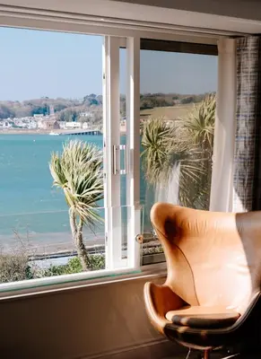 a chair in front of a window with a view of the ocean at Bijou Beachfront Gem, Rock in Padstow