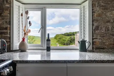 a kitchen counter with a window with a bottle of wine at Abel's Cottage gorgeous character barn Crackington in Crackington Haven