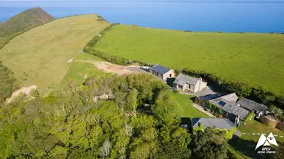 an aerial view of a house on a hill next to the ocean at Abel's Cottage gorgeous character barn Crackington in Crackington Haven
