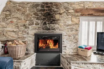 a stone wall with a fireplace in a living room at Abel's Cottage gorgeous character barn Crackington in Crackington Haven