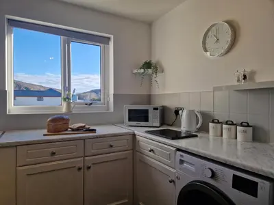 a kitchen with a counter and a microwave and a window at Harbour View apartment in Portreath in Portreath
