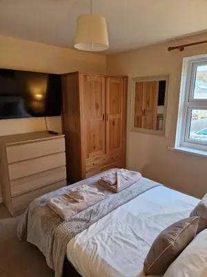 a bedroom with a bed with a dresser and a window at Harbour View apartment in Portreath in Portreath