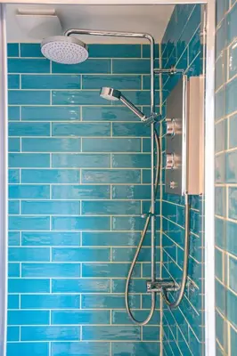 a blue tiled shower with a shower head in a bathroom at The Little Pines - 5 min walk to beach and sauna in Falmouth