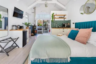 a bedroom with a large bed and a kitchen at The Little Pines - 5 min walk to beach and sauna in Falmouth