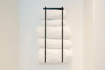 a stack of white towels on a rack at The Little Pines - 5 min walk to beach and sauna in Falmouth
