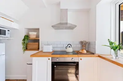 a kitchen with white cabinets and a stove top oven at Stylish cottage, log burner - Tregavone Cottage in Falmouth