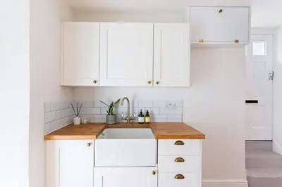 a kitchen with white cabinets and a sink at Stylish cottage, log burner - Tregavone Cottage in Falmouth