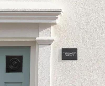 a sign on the side of a building with a door at Stylish cottage, log burner - Tregavone Cottage in Falmouth