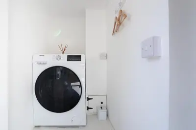a white washing machine in a white room at Stylish cottage, log burner - Tregavone Cottage in Falmouth
