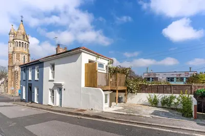 a white house on a street with a clock tower at Stylish cottage, log burner - Tregavone Cottage in Falmouth