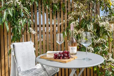 a table with two glasses of wine and grapes at Stylish cottage, log burner - Tregavone Cottage in Falmouth