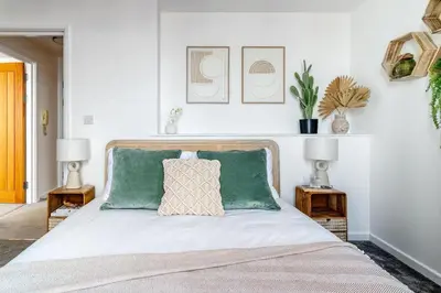 a bedroom with a bed with green pillows and two tables at Harbour sea views in town centre - 3 Headland View in Falmouth