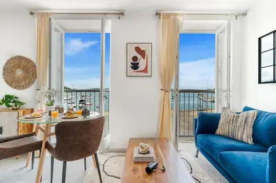 a living room with a blue couch and a table at Harbour sea views in town centre - 3 Headland View in Falmouth