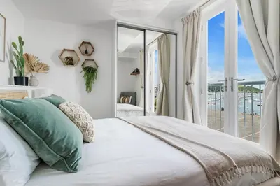 a bedroom with a large bed and a balcony at Harbour sea views in town centre - 3 Headland View in Falmouth