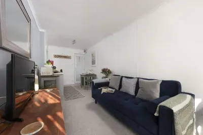 a living room with a blue couch and a tv at Olive Cottage, Carbis Bay - Parking Nearby, Free WiFi, Coffee Machine - Couples Retreat in Carbis Bay