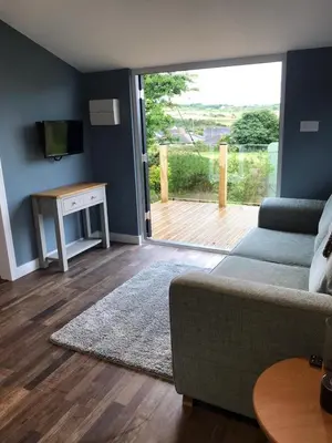a living room with a couch and a sliding glass door at Honeysuckle Cabin in Redruth