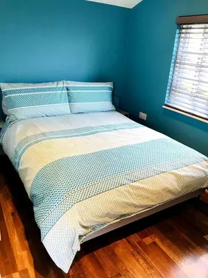 a bed in a bedroom with a blue wall at Honeysuckle Cabin in Redruth