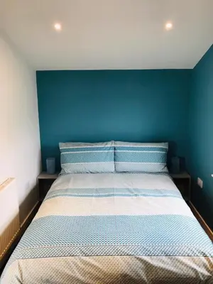 a bedroom with a bed with a blue wall at Honeysuckle Cabin in Redruth