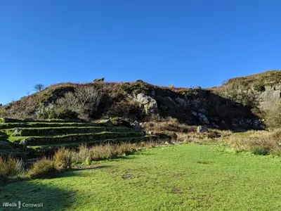 a field of grass with a hill in the background at Honeysuckle Cabin in Redruth