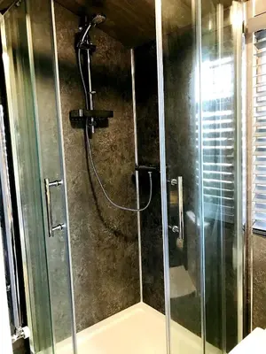 a shower with a glass door in a bathroom at Honeysuckle Cabin in Redruth