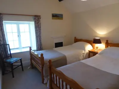 a bedroom with two beds and a window at Lower Tresmorn Cottage in Crackington Haven