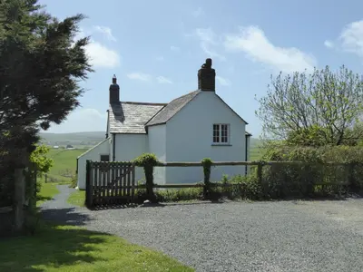 a white house with a fence in front of it at Lower Tresmorn Cottage in Crackington Haven