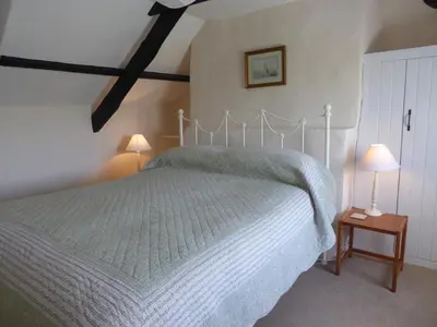 a bedroom with a bed and two lamps on tables at Lower Tresmorn Cottage in Crackington Haven