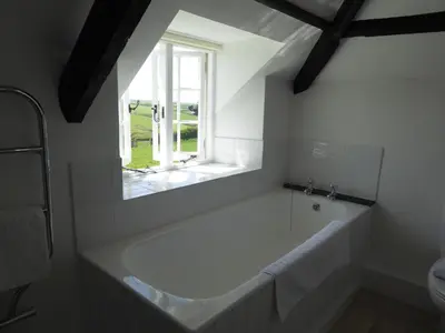 a white bath tub in a bathroom with a window at Lower Tresmorn Cottage in Crackington Haven