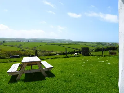 a picnic table in a field of green grass at Lower Tresmorn Cottage in Crackington Haven