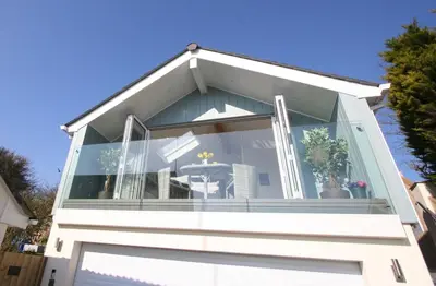 a house with a large window with a table at Kittiwake Retreat, a luxury escape by the sea! in Gorran Haven