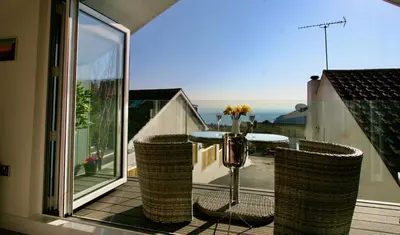 a balcony with a table and a view of the ocean at Kittiwake Retreat, a luxury escape by the sea! in Gorran Haven