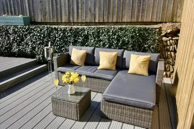 a patio with a blue couch and a table with yellow pillows at Kittiwake Retreat, a luxury escape by the sea! in Gorran Haven