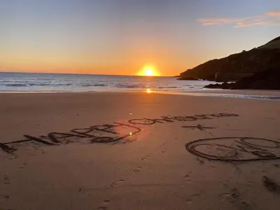 words written in the sand on a beach at sunset at Kittiwake Retreat, a luxury escape by the sea! in Gorran Haven