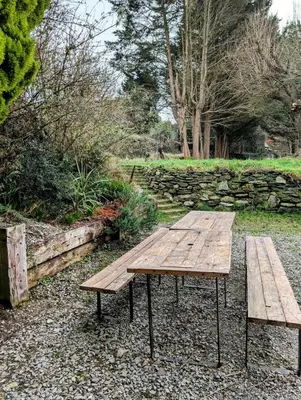 a wooden picnic table and bench in a garden at Ramble & Rye - The Nest in Talland