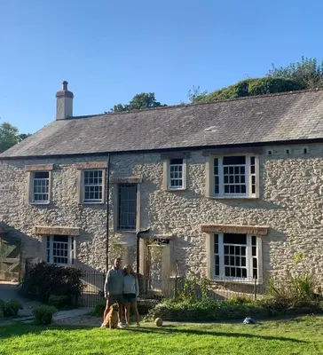 a family standing in front of a stone house at Ramble & Rye - The Nest in Talland