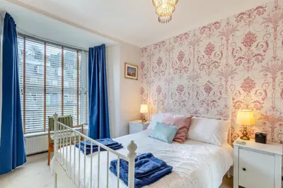 a bedroom with a bed with blue curtains and a crib at 3 Bed in St. Ives oc-c30654 in St Ives