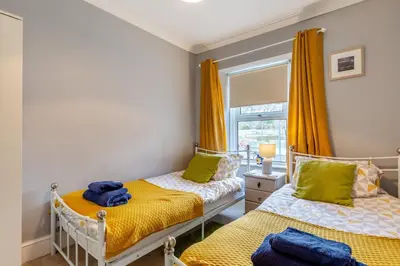 two beds in a bedroom with yellow curtains at 3 Bed in St. Ives oc-c30654 in St Ives