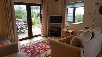 a living room with a couch and a television at 2br-sleeps4-pool-freeparking-trenythonestate in Par