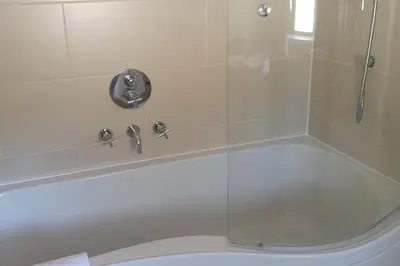a bathroom with a shower and a tub with a toilet at 2br-sleeps4-pool-freeparking-trenythonestate in Par
