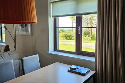 a living room with a table and a window at 2br-sleeps4-pool-freeparking-trenythonestate in Par