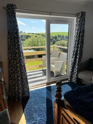 a bedroom with a sliding glass door to a balcony at Valley View in Port Isaac