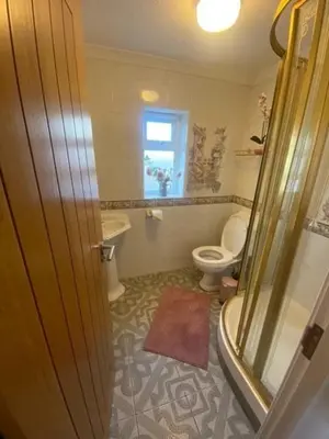 a bathroom with a shower and a toilet and a window at Valley View in Port Isaac